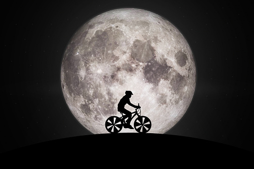 Silhouette of man Cycling on the moon.Elements of this image furnished by NASA.