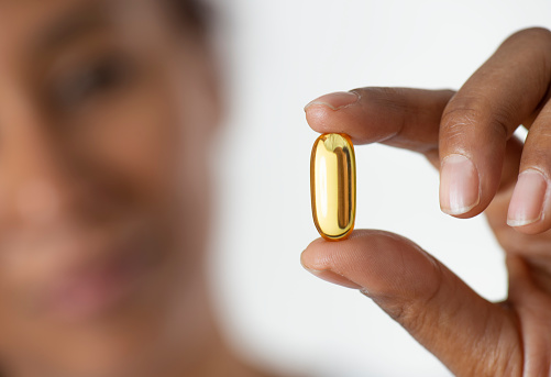 African woman holding pill, close-up.