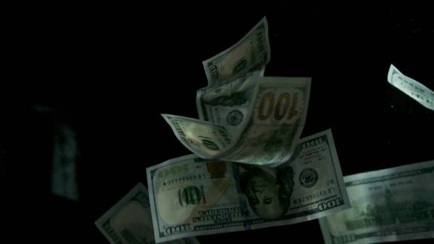 istock Falling flying american dollar banknotes on a black background 1217640739