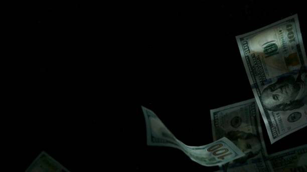 istock Falling flying american dollar banknotes on a black background 1217640788