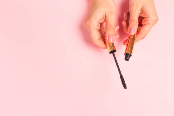 istock Beautiful young woman's hands holding  mascara on pastel pink background - Image 1217641461