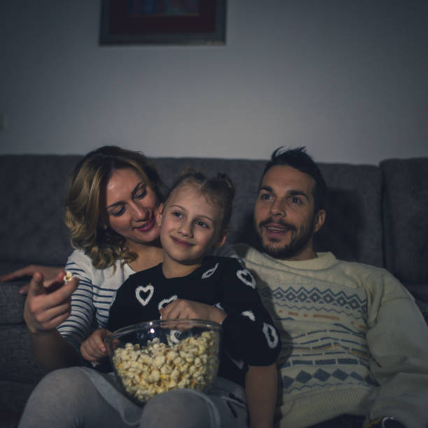 istock Family eating popcorn while watching tv at home 1217642405