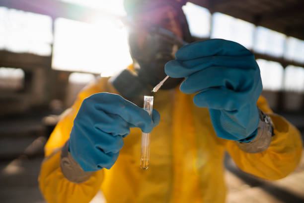 Taking samples of the virus Man in protective workwear examining toxic substances at the radioactive ruined building. soil sample stock pictures, royalty-free photos & images