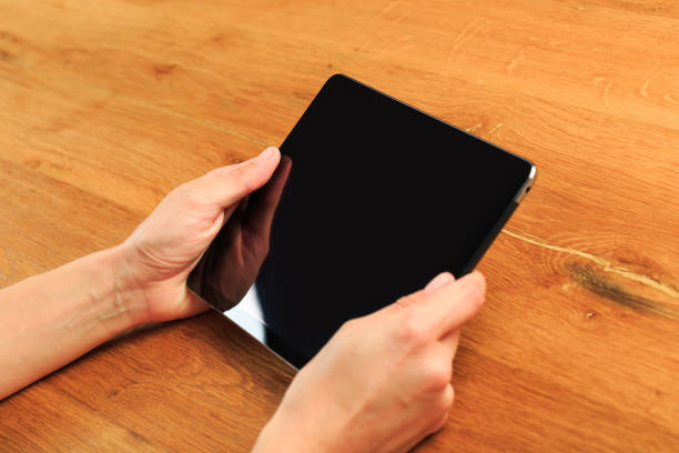 istock female hands holding tablet on wooden background - Image 1217644265