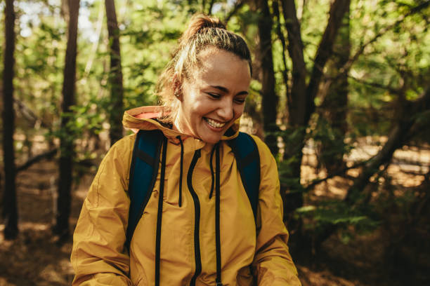 istock Woman with backpack standing in forest and smiling 1217644782