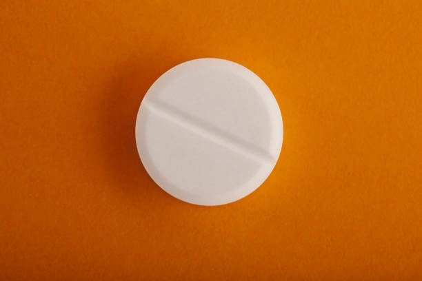 istock White round medical pill on yellow / orange background 1217646175