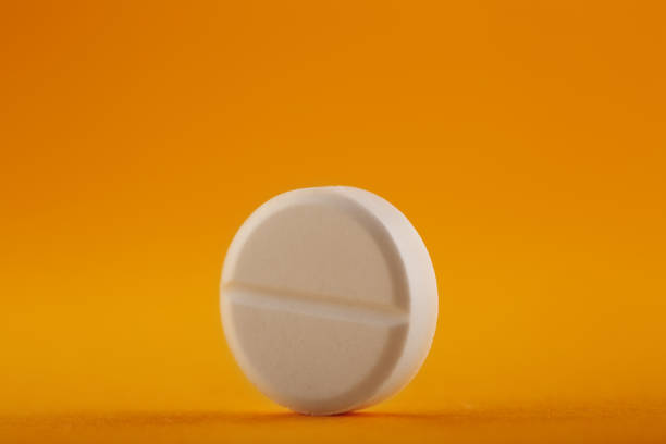 istock White round medical pill on yellow / orange background 1217646179
