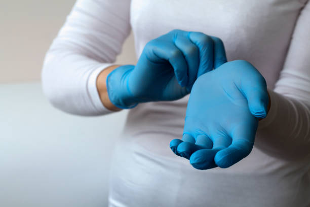 woman puts on protective blue gloves. Medical healthcare. Doctor hands in gloves in hospital. Professional medicine health clinic practitioner. People in white uniform in lab. copy space woman puts on protective blue gloves. Medical healthcare. Doctor hands in gloves in hospital. Professional medicine health clinic practitioner. People in white uniform in lab. copy space surgical glove stock pictures, royalty-free photos & images