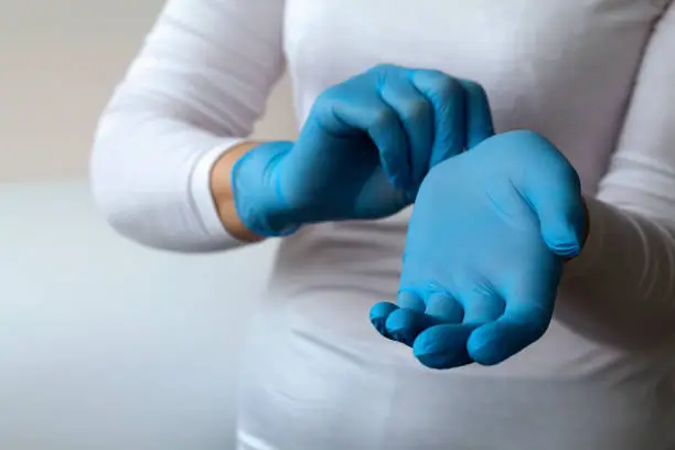 woman puts on protective blue gloves. Medical healthcare. Doctor hands in gloves in hospital. Professional medicine health clinic practitioner. People in white uniform in lab. copy space