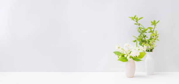 istock Home interior with decor elements. Branches with green leaves in a vase on a light background 1217649698