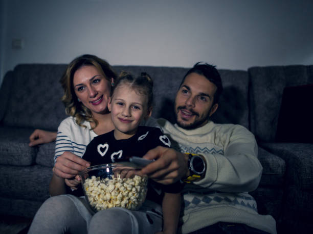 istock Family eating popcorn while watching tv at home 1217650602