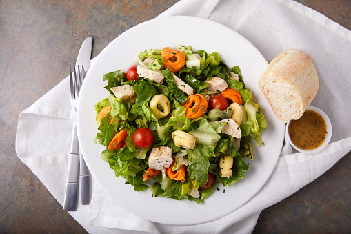 A plate of healthy and delicious Chicken Tortellini Salad with dressing on the side