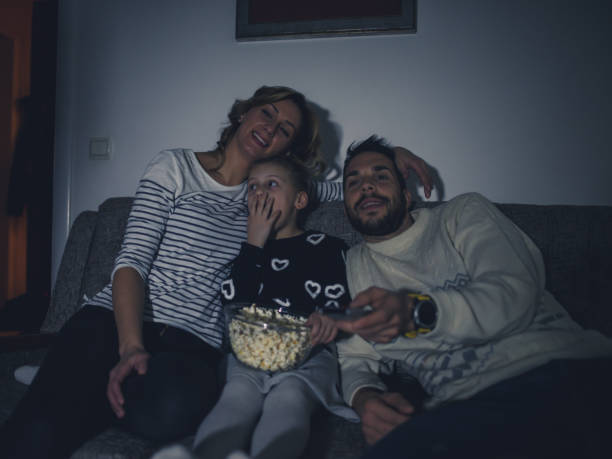 istock Family eating popcorn while watching tv at home 1217650932