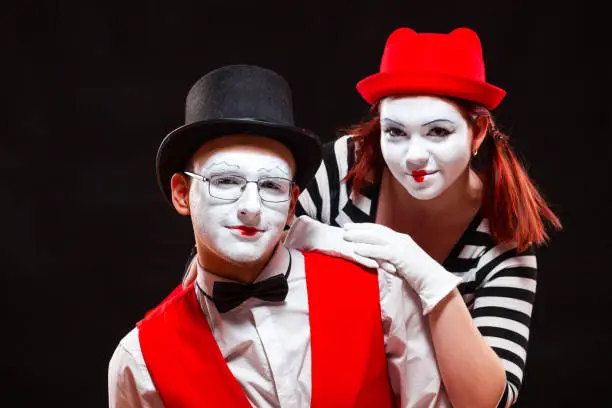 Portrait of two mime artists, isolated on black background. Woman and man look at camera. Symbol of happy marriage, sweet couple, family portrait.