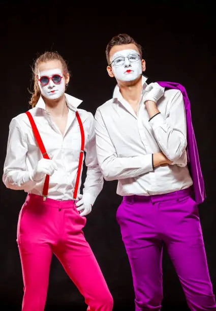Portrait of male mime artists, isolated on black background. Two man are posing adjusting suspenders and throwing jacket over his shoulder. Symbol of confidence, brothers, bro, friendship.
