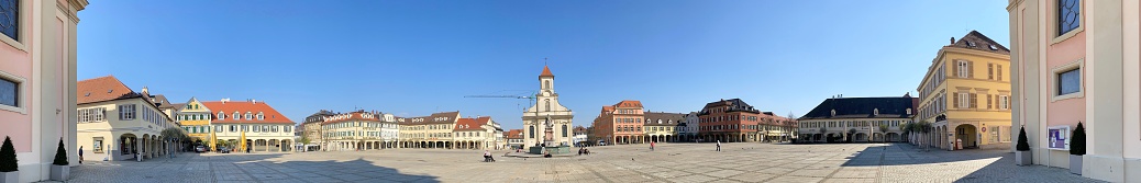 Ludwigsburg, Germany - April, 8 - 2020: Market square at Coronavirus lockdown. Few people outside at this sunny day, keeping the distance to each other. In the background center the catholic church to be seen.