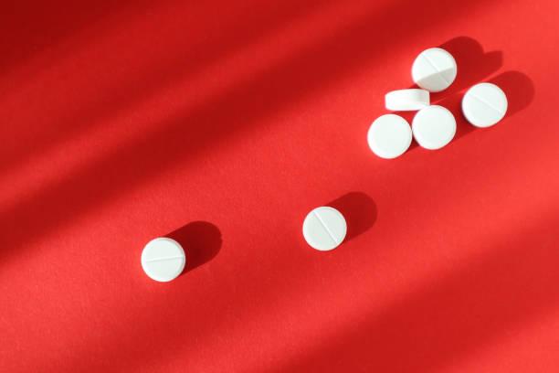 istock White pills on red background. Top view. Medicine concept. 1217654923