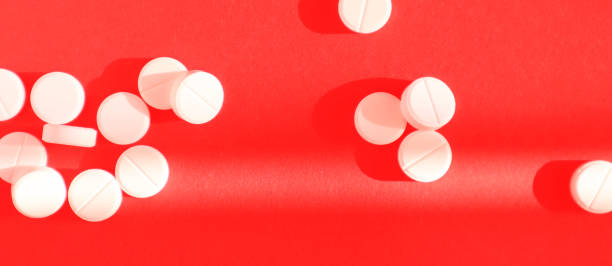 istock White pills on red background. Top view, banner. Medicine concept. 1217654945