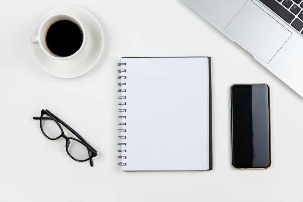 Modern working space, top view. Laptop, coffee, notebook, smartphone, glasses on white background, copy space, flat lay. Desktop of freelancer. Work from home, stay home, using technology concept