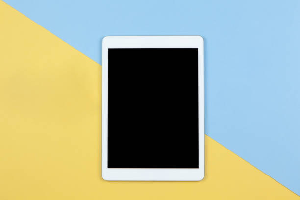 istock Tablet with empty screen on yellow and blue background, copy space, flat lay. Working space of freelancer. Freelance, planning of vacation, work from home, using technology concept. Horizontal 1217655761