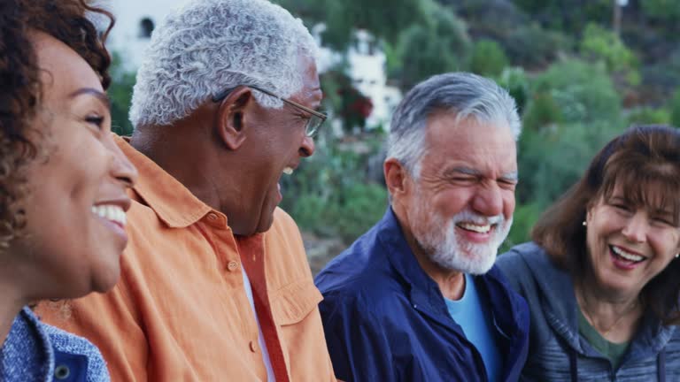 Group Of Senior Friends On Hike In Countryside Talking And Laughing Together