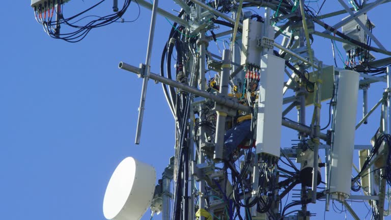 Close-Up of a Technician Assembling a Cell Phone Tower on a Clear, Sunny Day