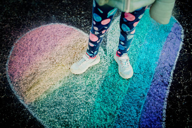 istock Child Standing in Rainbow Heart Chalk Drawing 1217660653