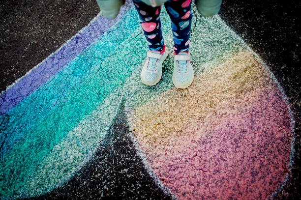 Little girl with black robber boots playing on paved sidewalk after drawing with chalk
