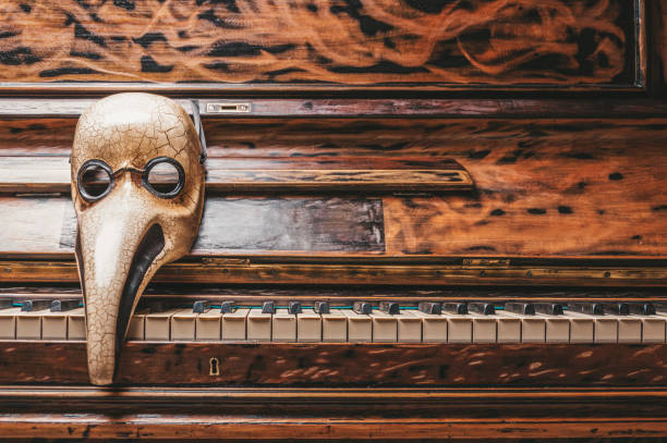 Abstraction of a venetian mask of a doctor lying on the piano keys. Concept of epidemic, concerts during quarantine. stock photo