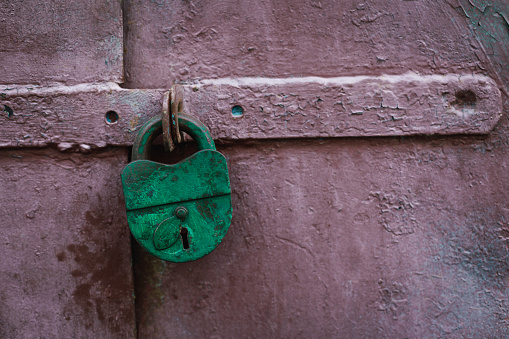 Old green lock on a rustic grungy door. Close-up.