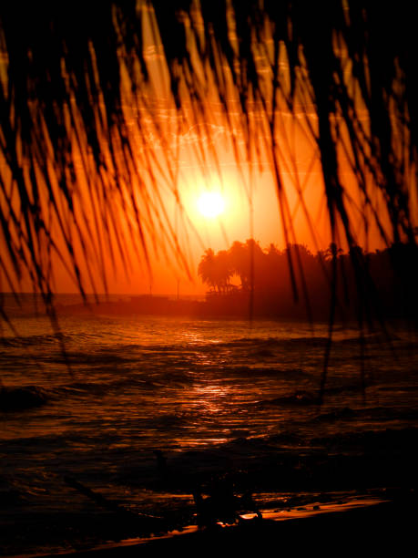 Sunset reflected in the water and stones in the sand of El Tunco beach, Sunzal, El Salvador.