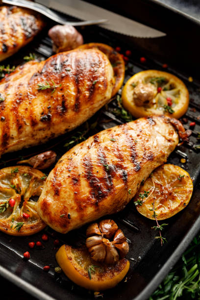 grilled chicken breasts with thyme, garlic and lemon slices on a grill pan close up - chicken breast chicken grilled chicken protein imagens e fotografias de stock
