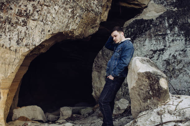 istock Young lonely man sitting on rock 1217667630