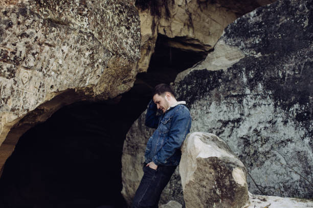 istock Young lonely hipster man sitting on rock 1217667724