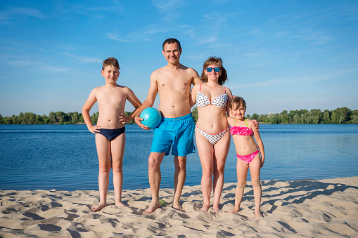 A happy family on the beach.  People with a volleyball on the river bank.  The concept is a healthy lifestyle.
