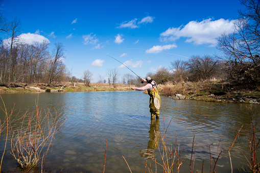 A teen fly-fisherman out on a river in the spring.
