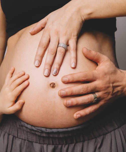 pregnant woman holding her belly with her son and husband