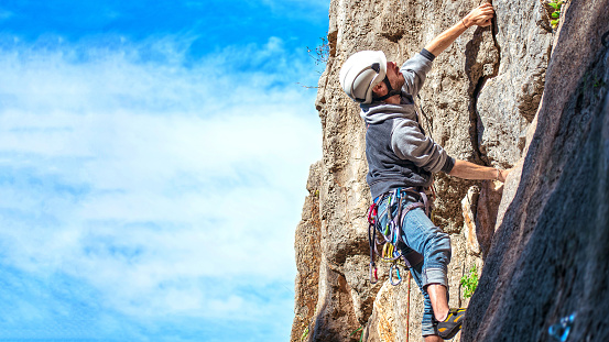 One sportsman mountain climbing. Physical activity in the countryside. Risky sports. Mountain climb or climbing with safety equipment in Murcia, Spain.