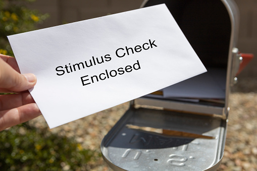 A person retrieves their stimulus check from the mailbox.