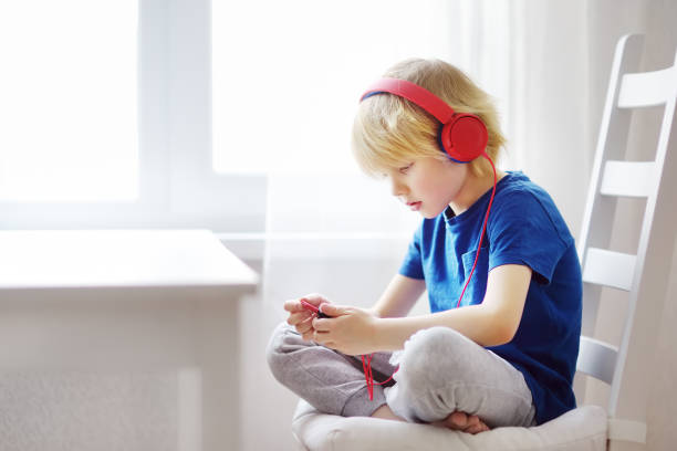 criança pré-escolar gosta de ouvir música ou audiobook usando seus fones de ouvido em casa. - creative thinking audio - fotografias e filmes do acervo