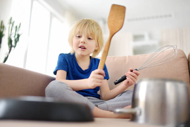 istock Mischievous preschooler boy play the music using kitchen tools and utensils at home during quarantine. Funny drum part from child. Entertainment a kids at home. 1217680953