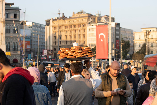 Istanbul, Turkey - October-27.2019: Man sells bagels in the tray on his head. Trying to make money. There are people around him.