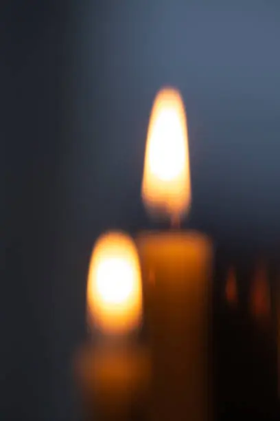 White candle burning on a black background.