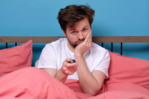 istock man in bed using remote control for changing tv channel or air conditioning feeling bored 1217683593