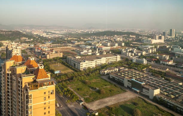 Evening shot over several rows of factories, Suzhou, China. Suzhou China - May 3, 2010: Aerial morning shot over industrial and business district with plants and factories. Wider view over city with hazy mountains on horizon. lake tai stock pictures, royalty-free photos & images