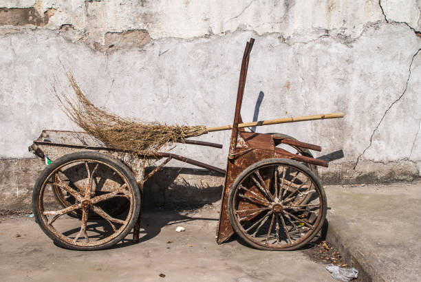 Two rusted metal wheelbarrows, Suzhou, China. Suzhou China - May 3, 2010: Closeup of 2 brown rusted wheelbarrows set against white wall and broom made of twigs. lake tai stock pictures, royalty-free photos & images