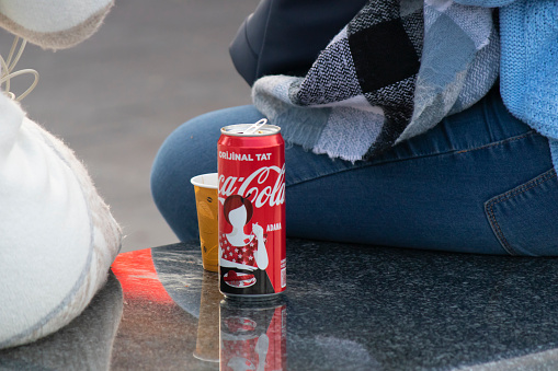 Istanbul, Turkey - November-02.2019: The coca cola can of cola that people drink while eating. Made of red aluminum. It stands on black marble.