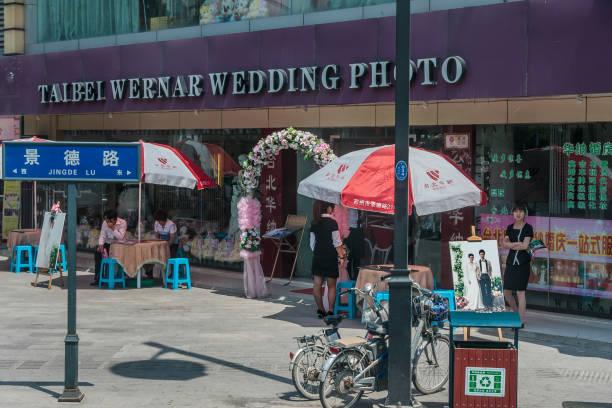 Row of small shops in shopping street, Suzhou, China. Suzhou China - May 3, 2010: Row of small shops waiting for customers, one being wedding photography with spot to shoot. People, bikes, umbrella and table with stairs. lake tai stock pictures, royalty-free photos & images