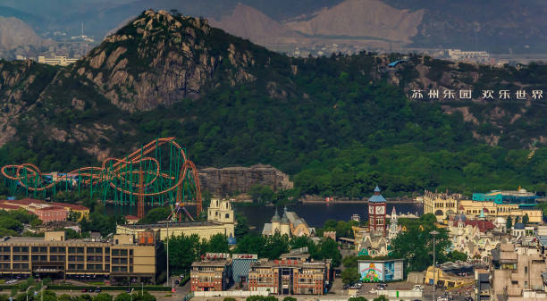 Suzhou Amusement Land aerial view, China. Suzhou China - May 3, 2010: Aerial overview shot of Amusement Land with roller coaster and other attraction and buildings. Back is partly green covered mountain and more of them on horizon. lake tai stock pictures, royalty-free photos & images