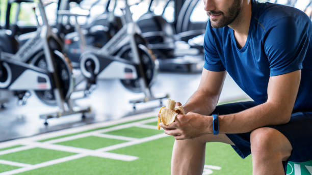 青い服を着た選手は運動後にバナナを食べます。 - muscular build food healthy eating human muscle ストックフォトと画像